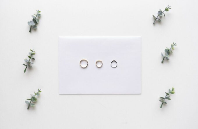 Drei Ringe auf einer weißen Karte, umgeben von Eukalyptusblättern.