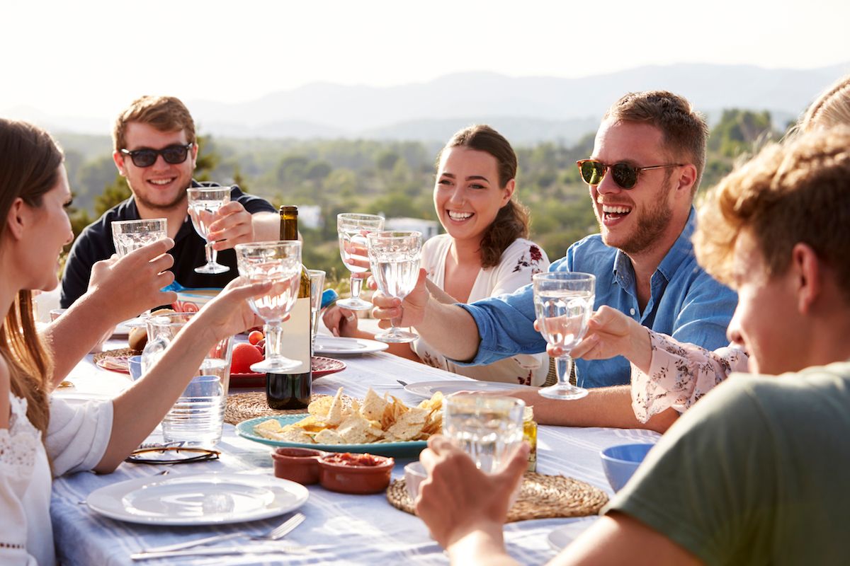 Eine Gruppe von Freunden stößt an einem Tisch im Freien an.