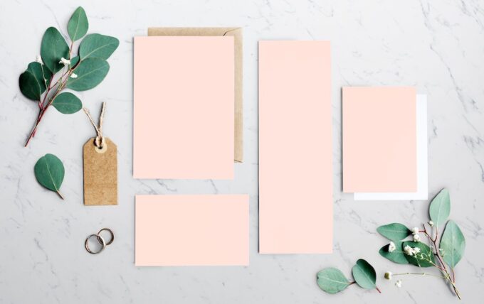 Eukalyptusblätter und rosafarbenes Briefpapier auf einem Marmortisch.