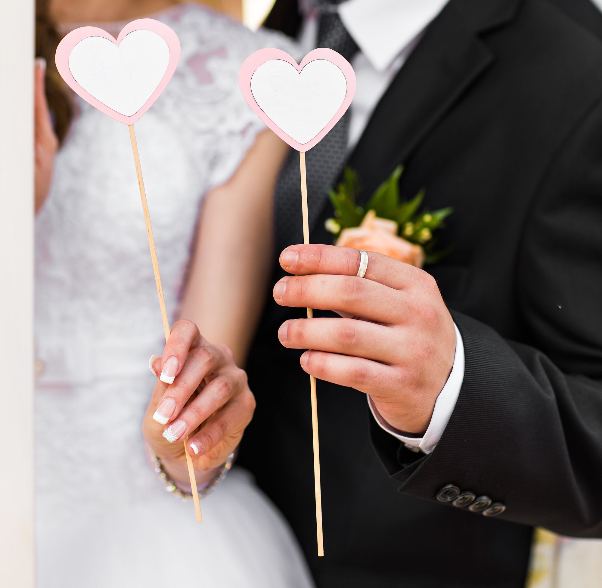 Eine Braut und ein Bräutigam halten herzförmige Stöcke in der Hand.