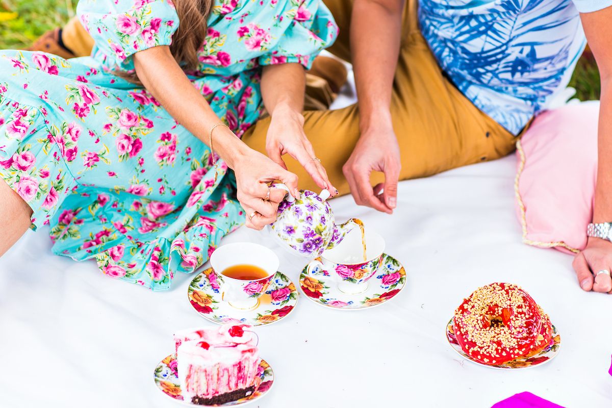 Ein Paar sitzt auf einer Decke mit einer Tasse Tee und Donuts.