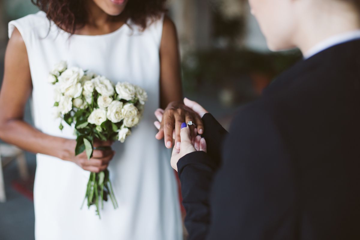 Eine Frau steckt ihren Ehering an den Finger einer anderen Frau.