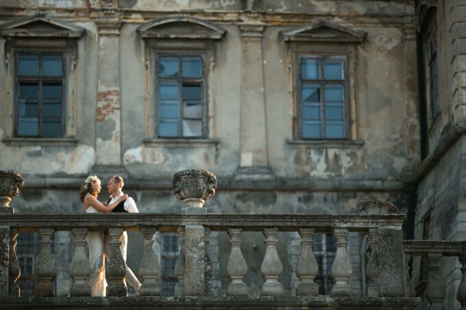 Eine Braut und ein Bräutigam stehen auf dem Balkon eines alten Schlosses.