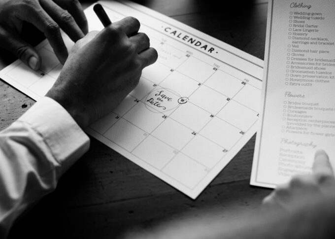 Ein Schwarz-Weiß-Foto eines Mannes, der in einen Kalender schreibt.