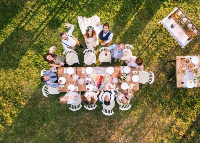 Eine Gruppe von Menschen sitzt um einen Tisch im Gras.