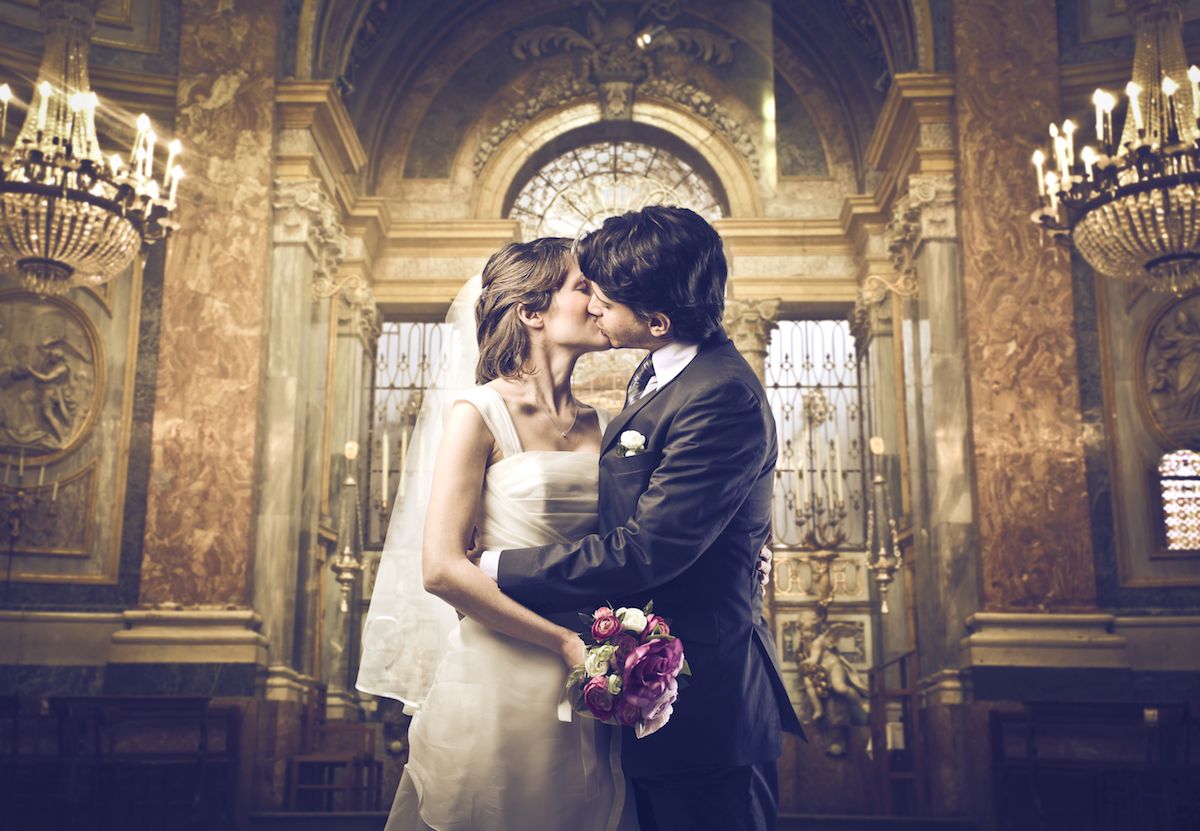 Eine Braut und ein Bräutigam küssen sich in einer Kirche.
