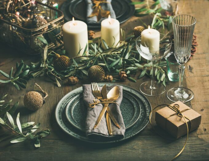 Weihnachtstischdekoration mit Kerzen und Grün auf einem Holztisch.
