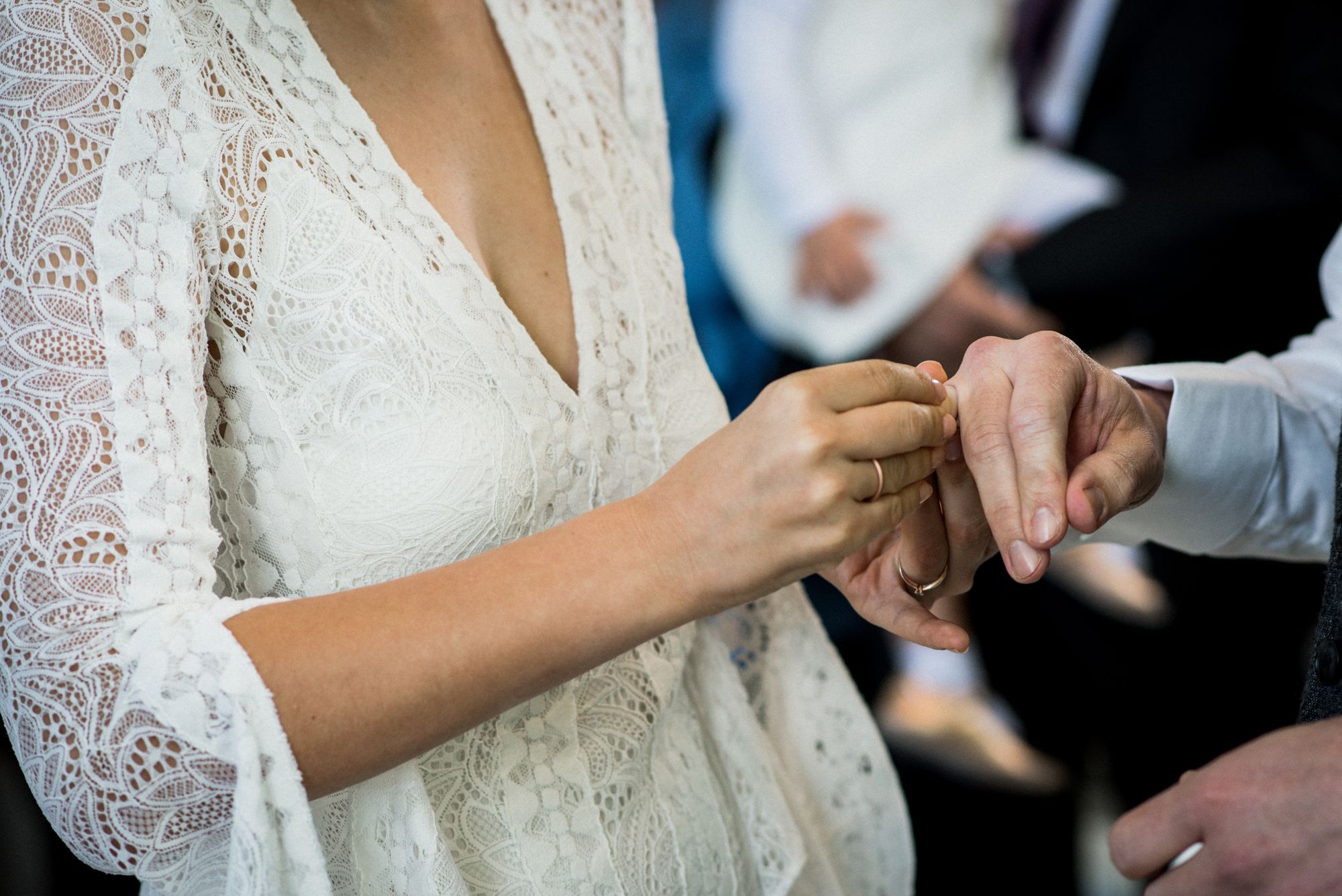 Eine Braut steckt einem Mann ihren Ehering an den Finger.