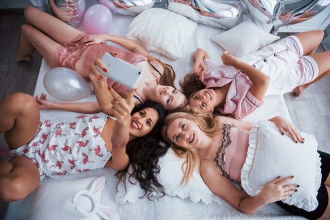 Eine Gruppe Mädchen liegt auf einem Bett und macht ein Selfie.