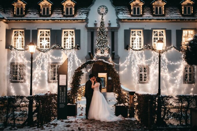 Ein Brautpaar steht nachts vor einem Schloss.