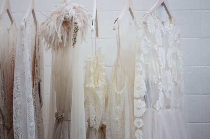 Eine Reihe weißer Brautkleider hängt an einer Wand.