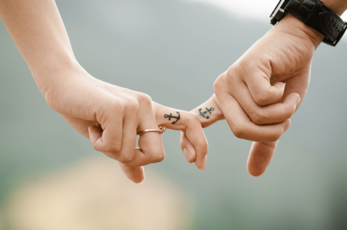 Ein Händchen haltendes Paar mit Tätowierungen an den Händen.