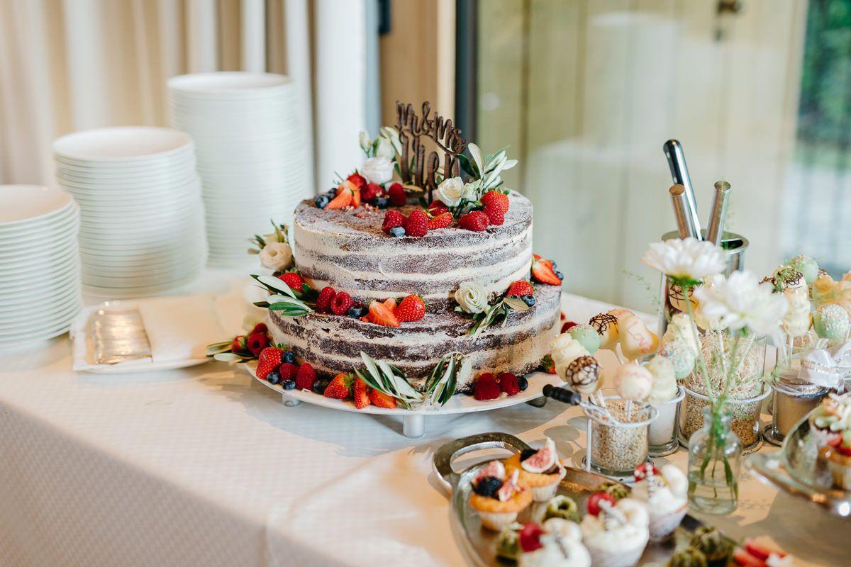 Eine Hochzeitstorte auf einem Tisch mit Obst darauf.