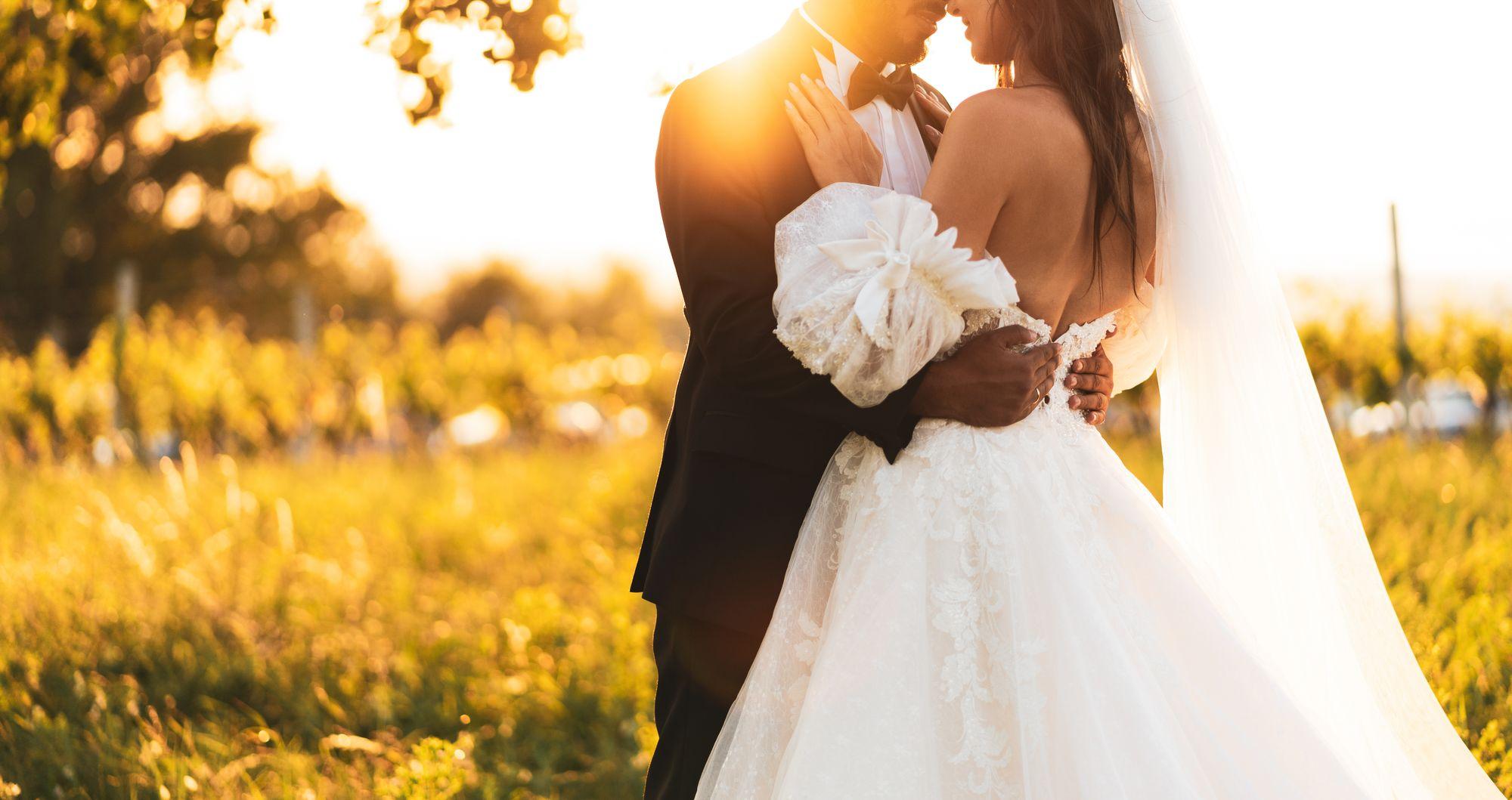 Eine Braut und ein Bräutigam umarmen sich bei Sonnenuntergang in einem Weinberg.