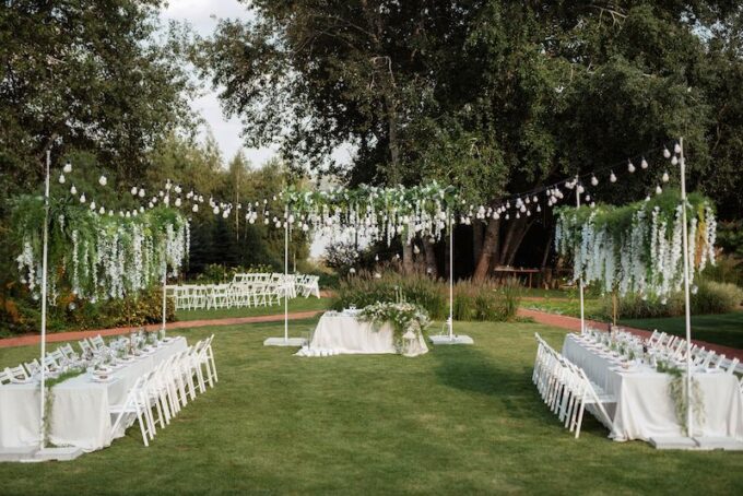Ein Hochzeitsempfang im Freien mit weißen Tischen und Stühlen.