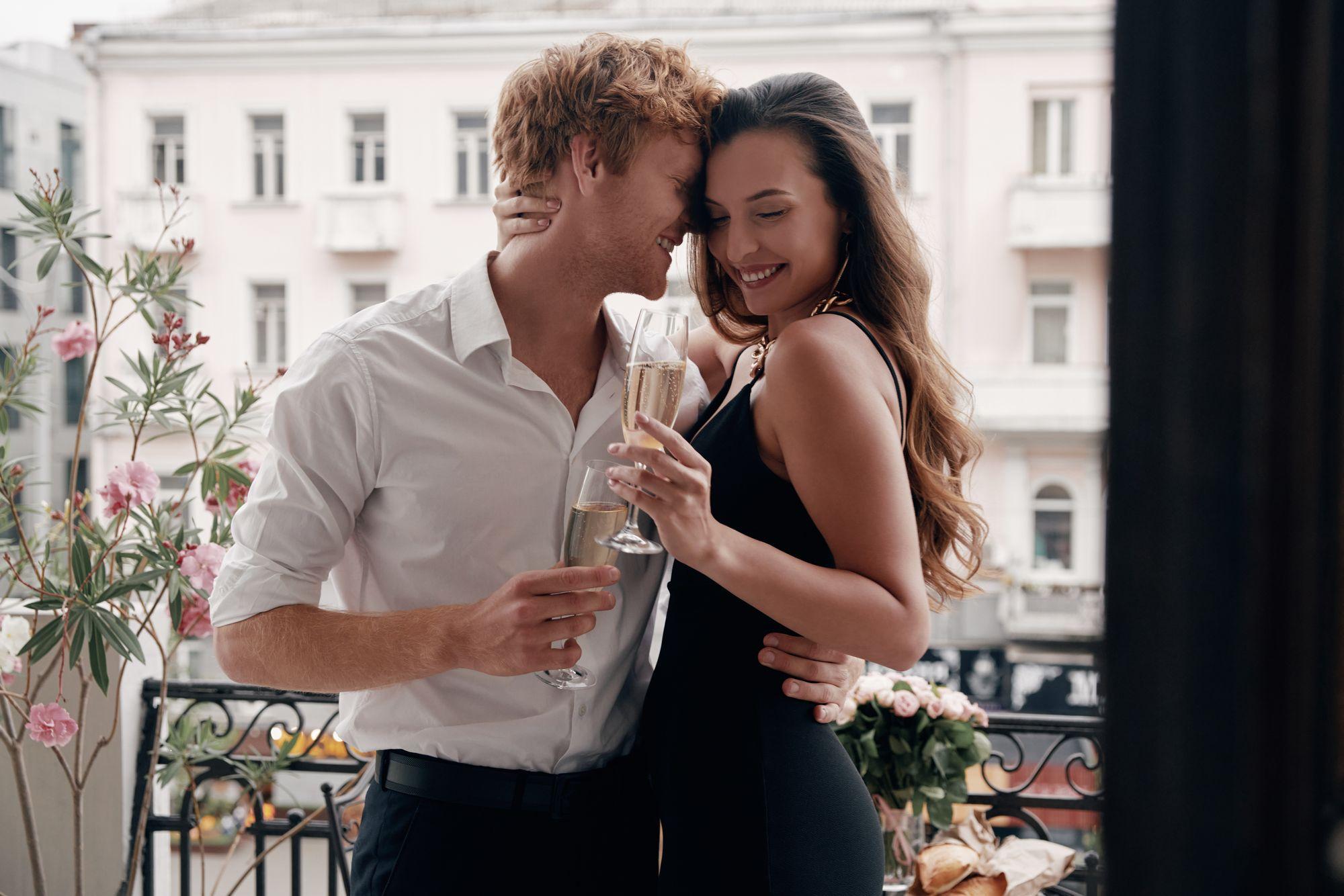 Ein Paar hält Champagnergläser auf einem Balkon.