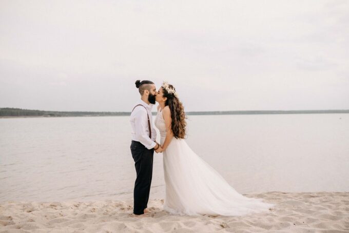 Ein Brautpaar küsst sich am Strand.