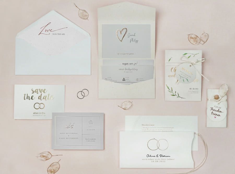 Ein weiß-goldenes Hochzeitsbriefpapier auf einem rosa Hintergrund.