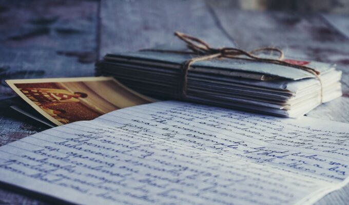 Ein Notizbuch mit handschriftlichen Notizen und Fotos liegt auf einem Holztisch.