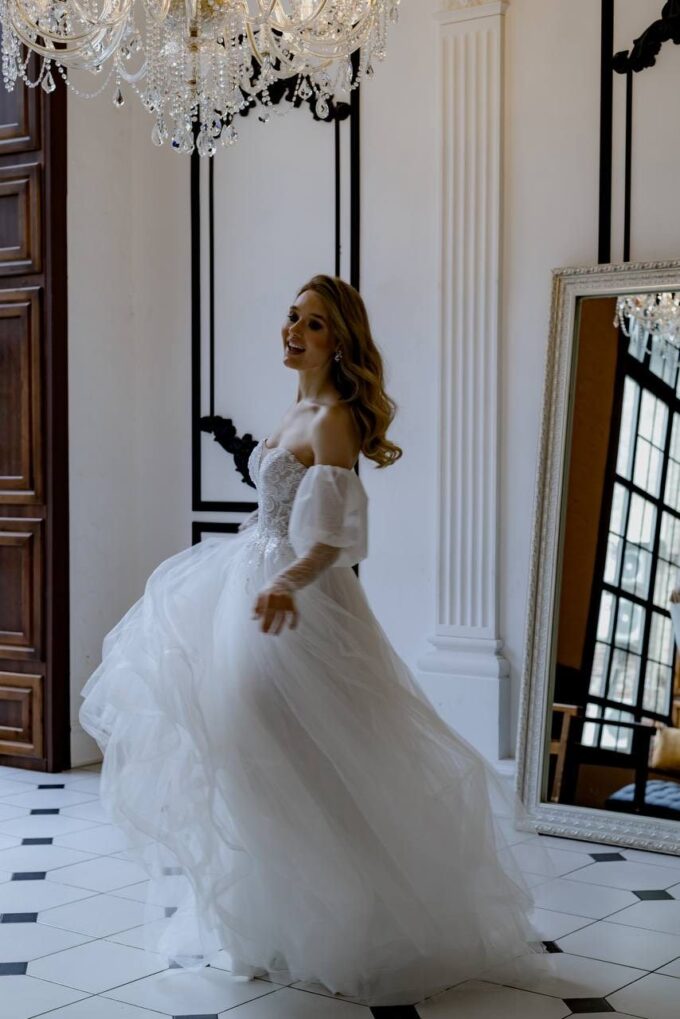 Eine Frau in einem Hochzeitskleid steht vor einem Spiegel.