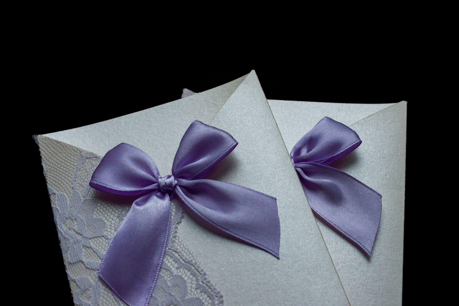 Hochzeitseinladung: Eine perlmuttfarbene Einladung mit lila Spitze