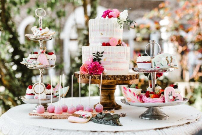 Eine Hochzeitstorte und Cupcakes auf einem Tisch im Garten.