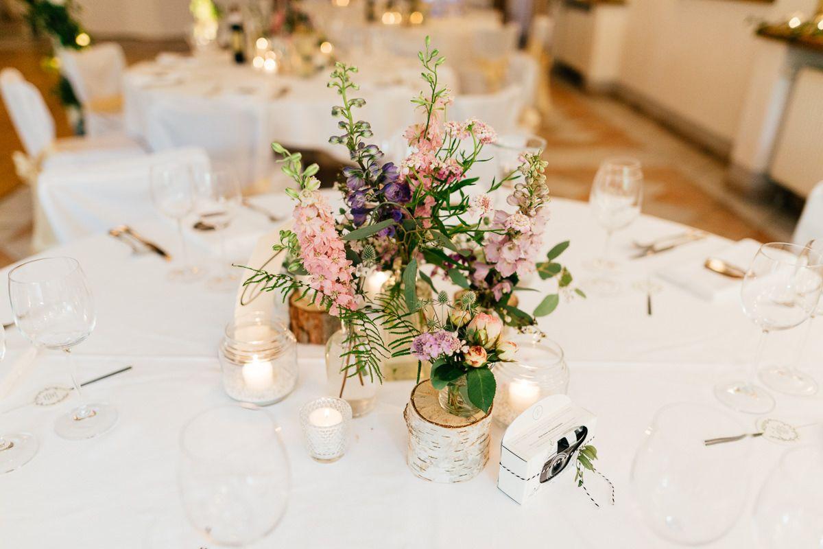Ein Tisch mit Blumen und Kerzen bei einer Hochzeitsfeier.