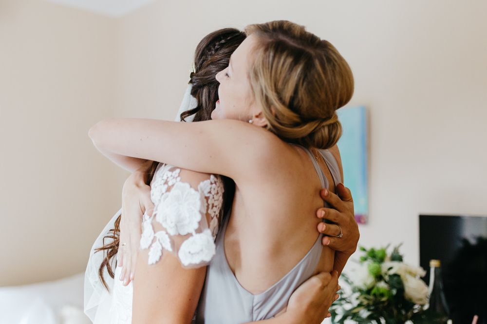 Eine Braut umarmt ihre Brautjungfer im Schlafzimmer.