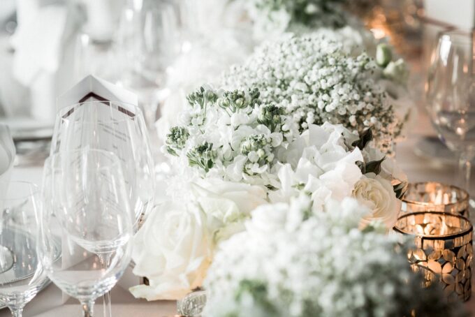 Ein mit weißen Blumen und Weingläsern gedeckter Tisch.