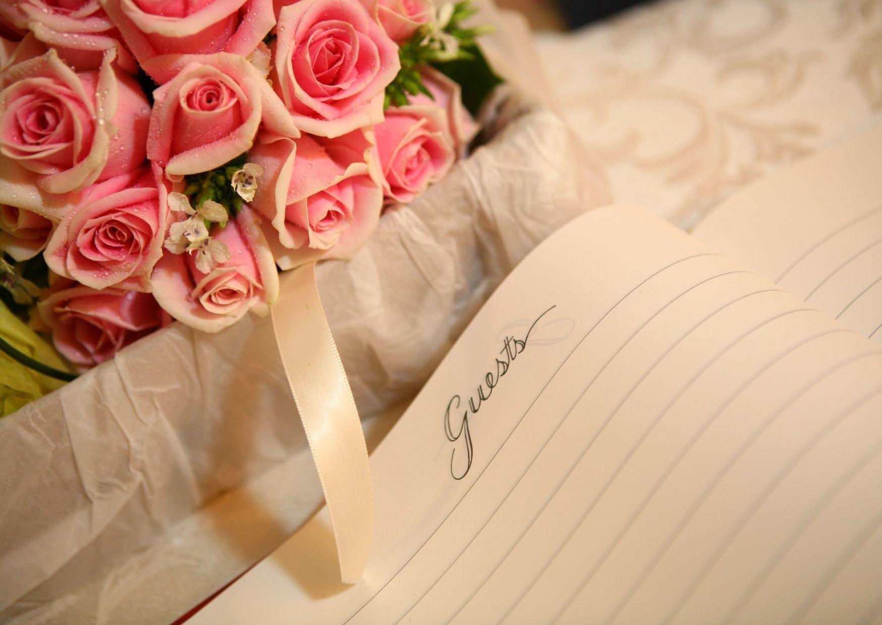 Ein Strauß rosa Rosen neben einem Notizbuch.
