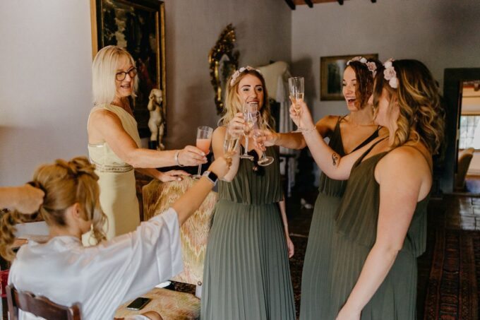 Brautjungfern stoßen in einem Raum mit Champagner an.