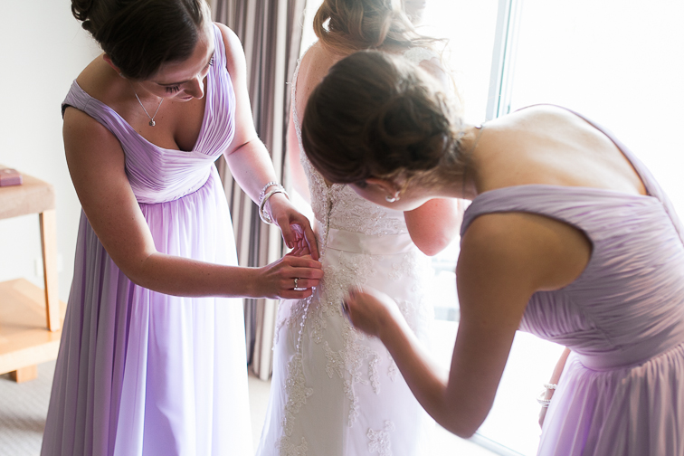 Kleid von der Braut wird von Trauzeugen zu geknoepft