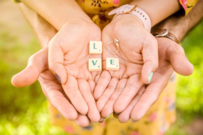 Ein Paar hält Händchen, auf denen das Wort „Liebe“ steht.