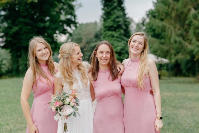 Vier Brautjungfern in rosa Kleidern posieren für ein Foto.