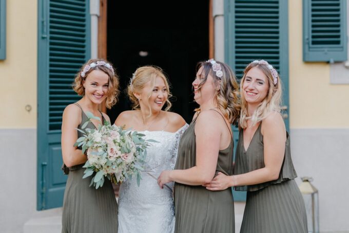 Vier Brautjungfern lachen vor einer Tür.