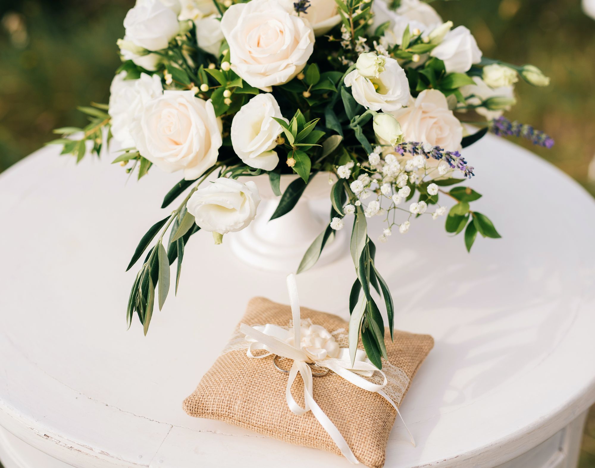 Weiße Blumen in einer weißen Vase auf einem weißen Tisch.