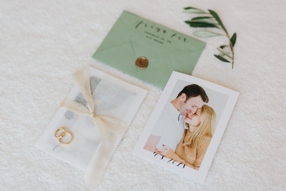 Eine Hochzeitseinladung mit einem Foto eines Paares und Eukalyptusblättern.