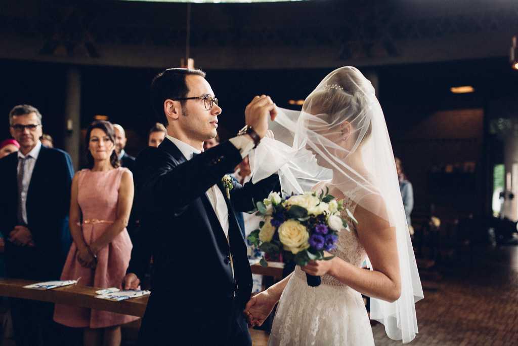 Eine Braut legt in einer Kirche ihren Schleier über einen Bräutigam.