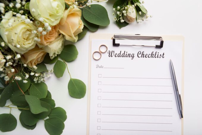 Eine Hochzeitscheckliste mit Blumen und einem Stift.