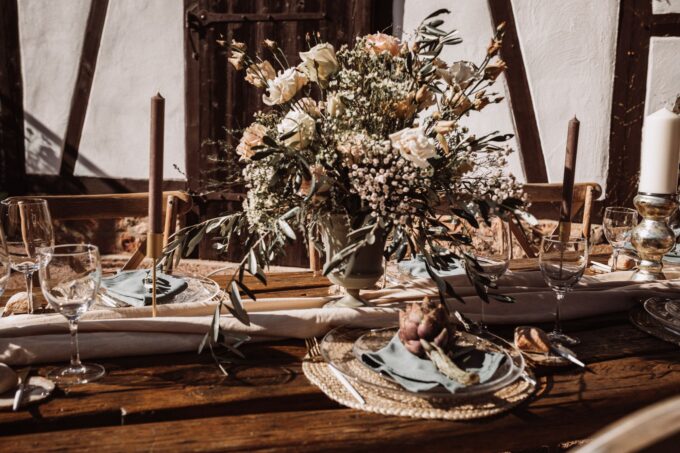 Ein gedeckter Tisch mit Kerzen und Blumen auf einem Holztisch.