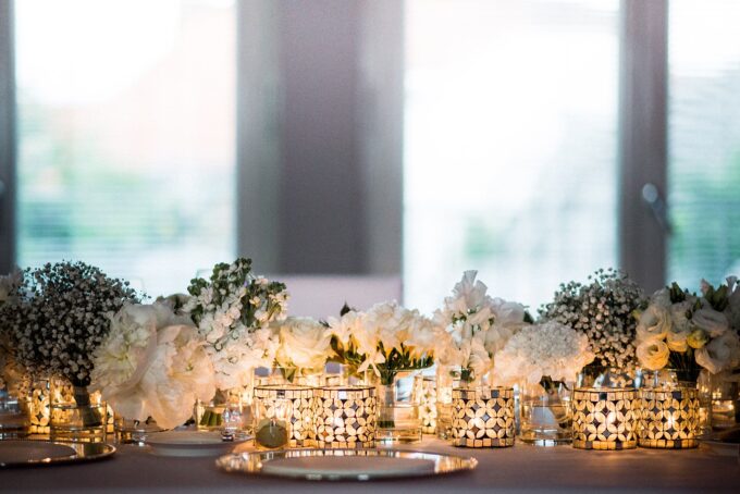 Ein weißer Tisch mit Kerzen und weißen Blumen.