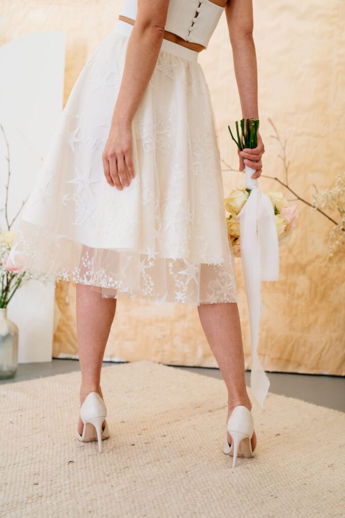 Eine Braut in einem weißen Hochzeitskleid hält einen Blumenstrauß.