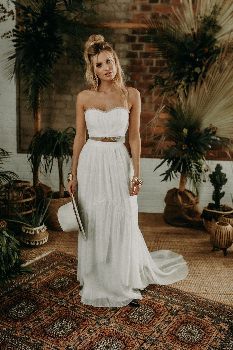 Eine Braut in einem weißen Hochzeitskleid steht vor einer Topfpflanze.