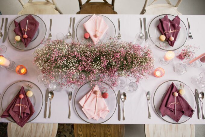 Ein Ostertisch mit rosa Blumen und Servietten.