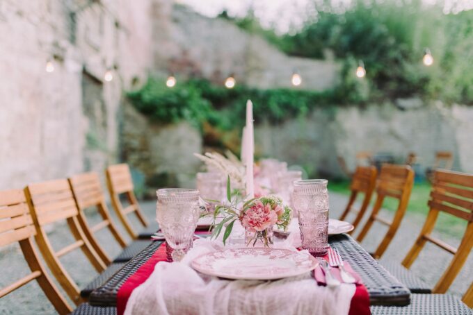 Ein mit rosa und weißen Tellern und Gläsern gedeckter Tisch.