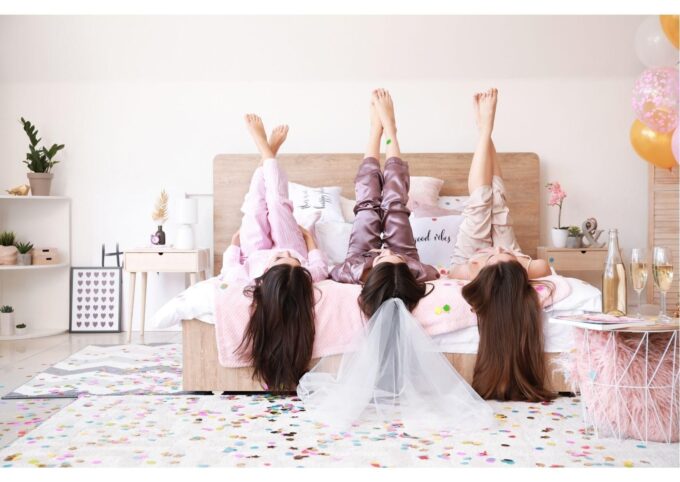 Eine Gruppe Mädchen im Pyjama auf einem Bett mit Luftballons und Konfetti.