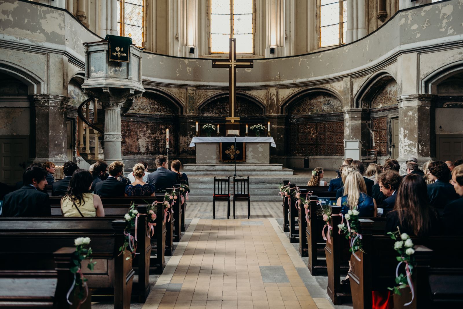 Eine Hochzeitszeremonie in einer Kirche mit Menschen, die in Kirchenbänken sitzen.