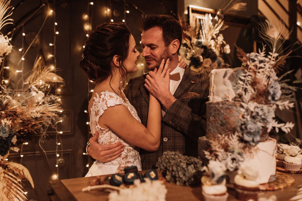 Eine Braut und ein Bräutigam küssen sich vor einer Torte.