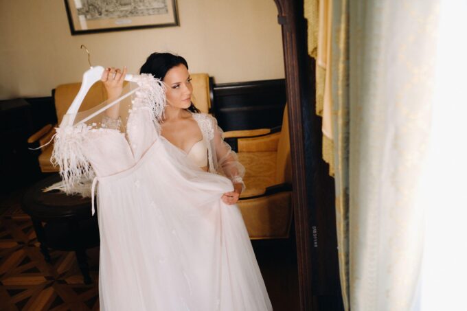 Eine Braut zieht in einem Zimmer ihr Hochzeitskleid an.