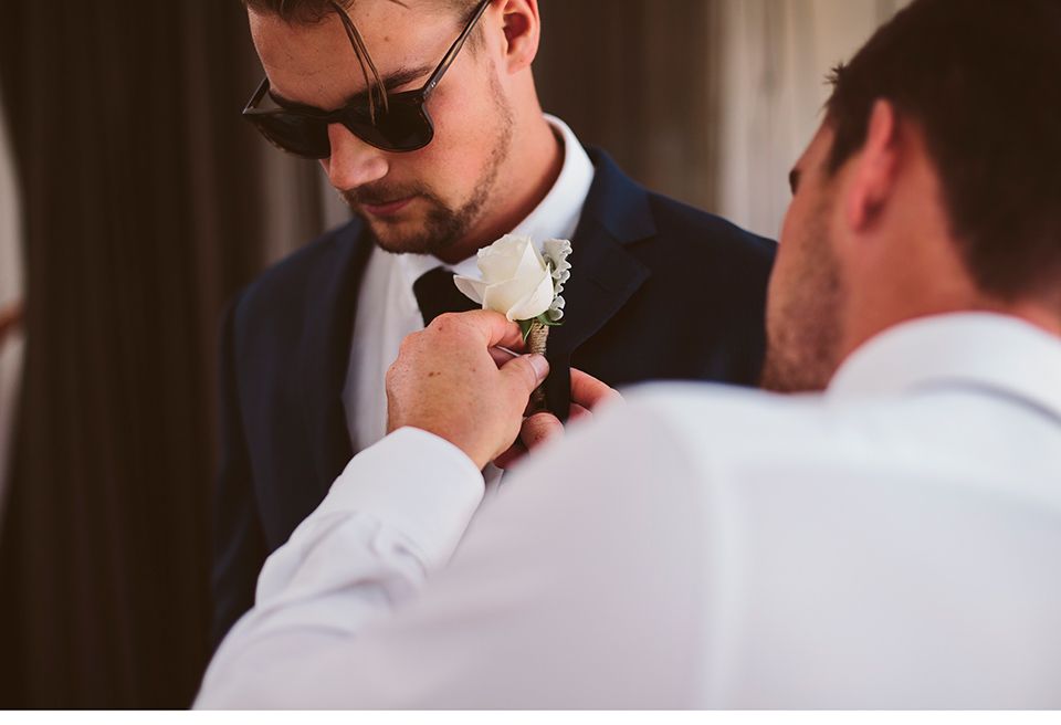 Der Bräutigam bekommt eine Ansteckblume an seinem Jackett befestigt.
